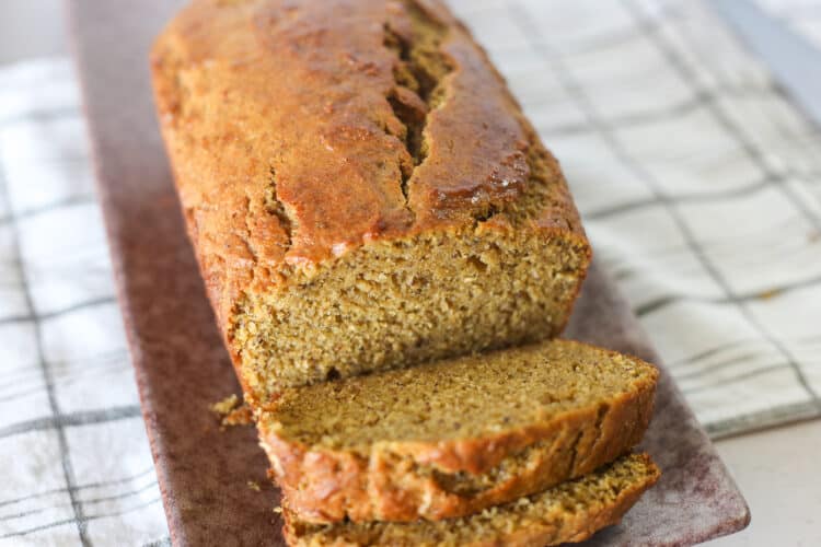 A loaf of banana pumpkin bread with two slices cut.