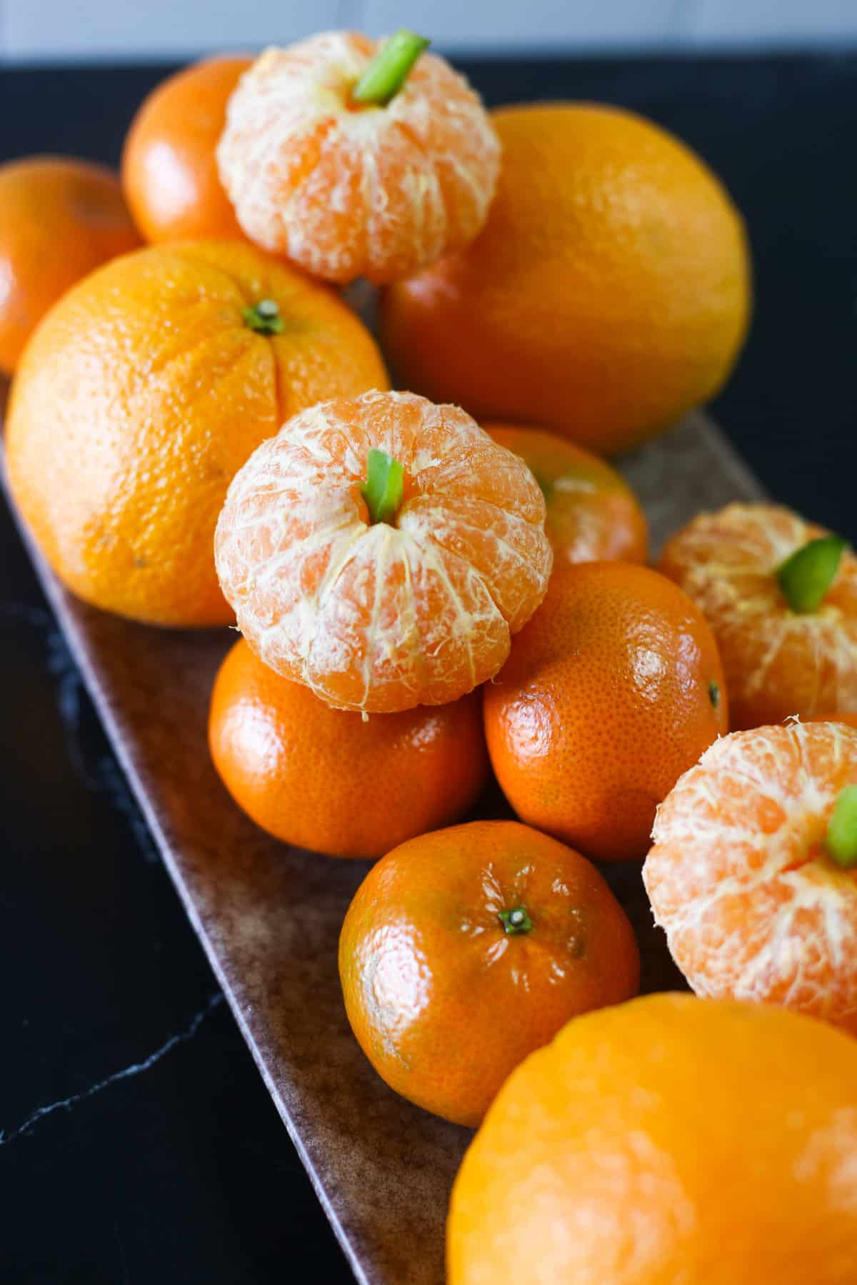 A platter of oranges, clementines, and clementine pumpkins.