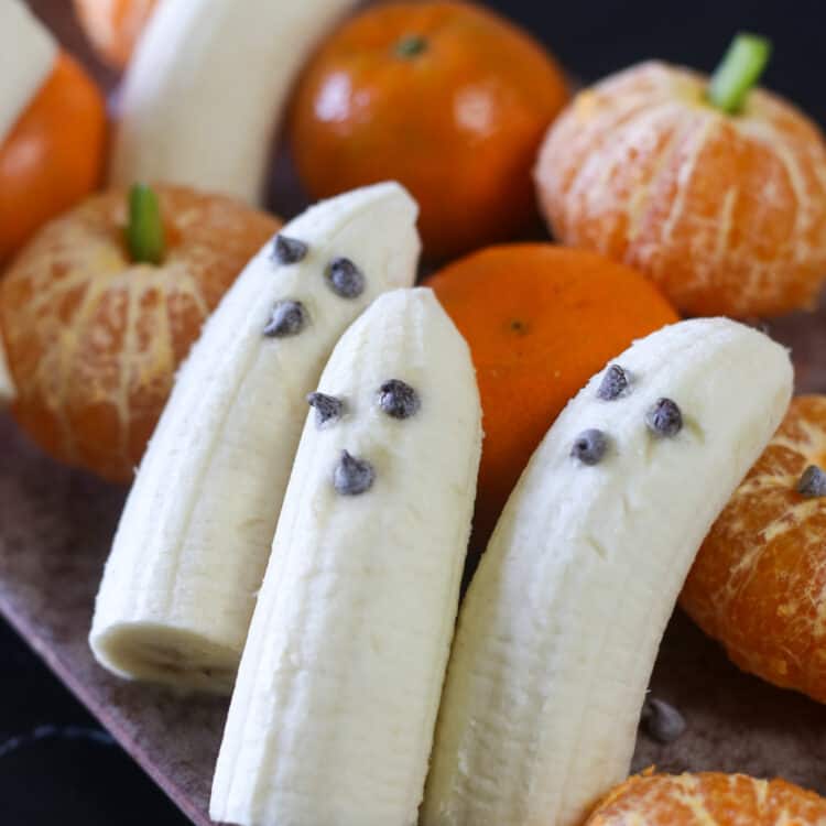Ghost bananas on a plate with clementine pumpkins.