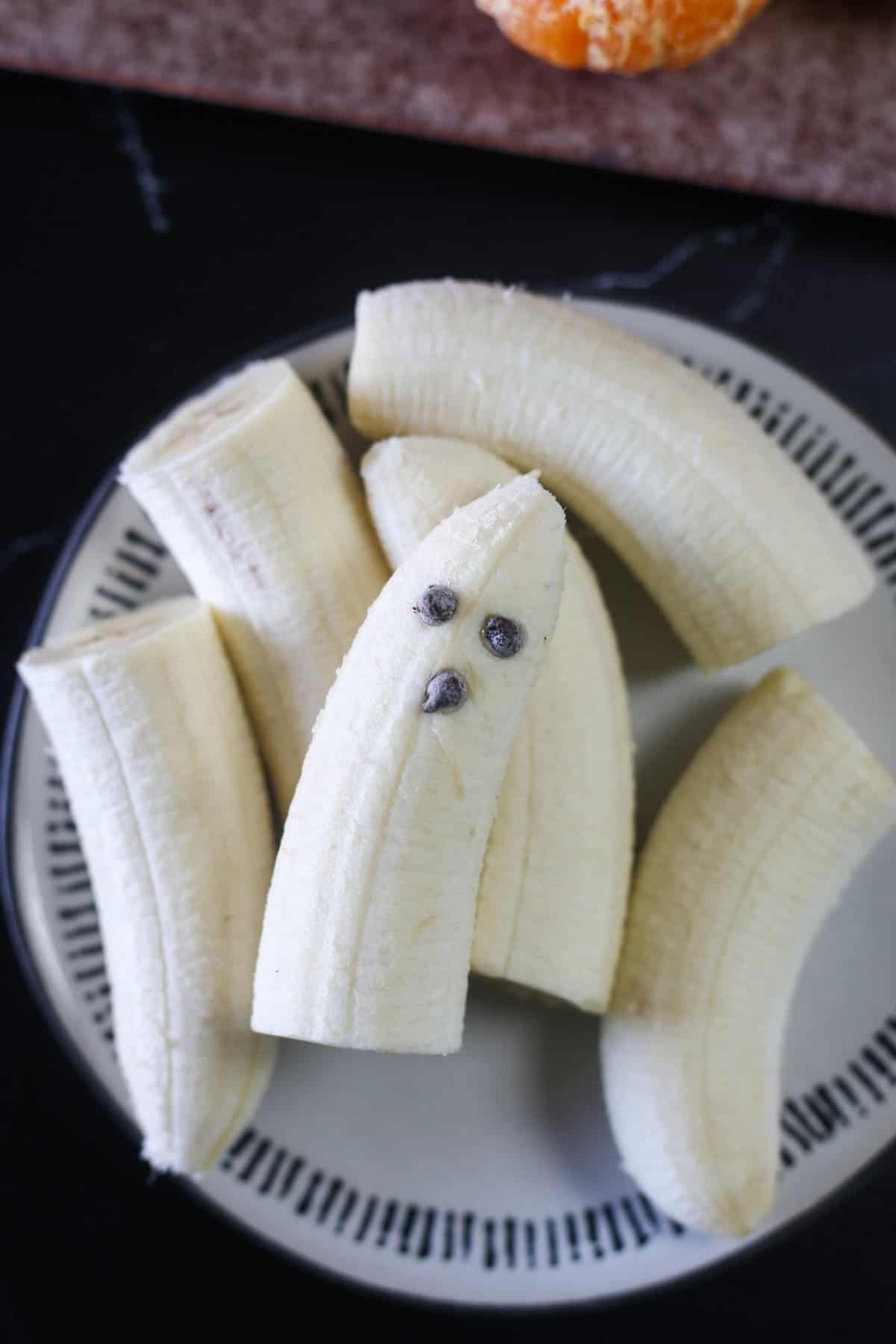 A banana with chocolate chips making a face on it. 