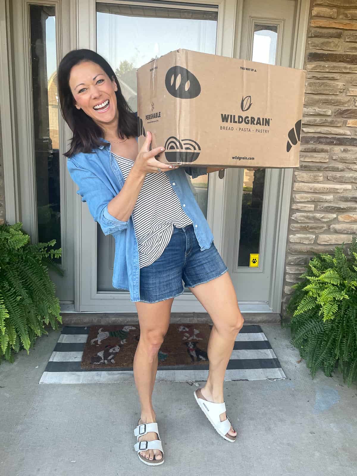 Polly Conner holding a wildgrain box on a front porch.