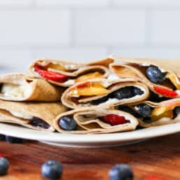 Fruit pizza roll ups stacked on a plate.