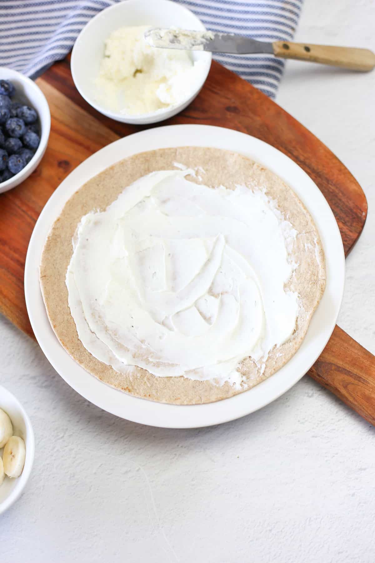 A tortilla with cream cheese spread on it. 