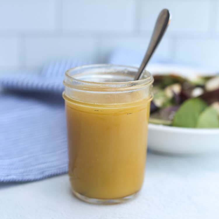 Honey Dijon salad dressing in a mason jar with a spoon.