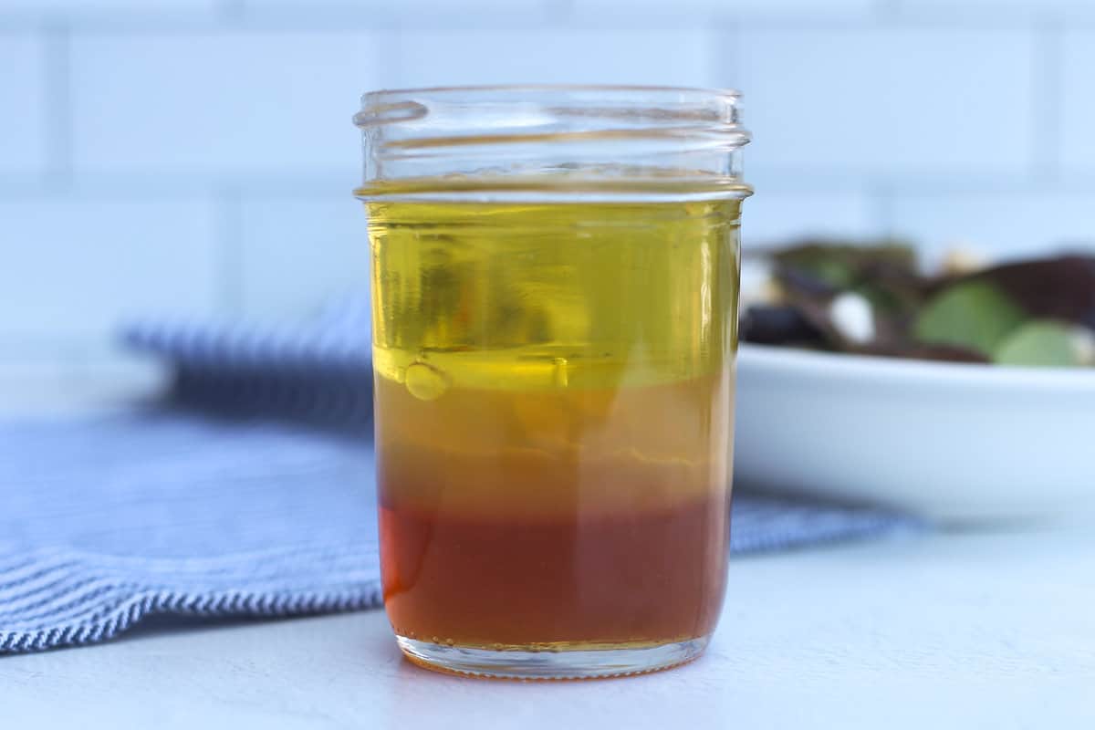 Ingredients for honey dijon salad dressing in a mason jar before mixing.