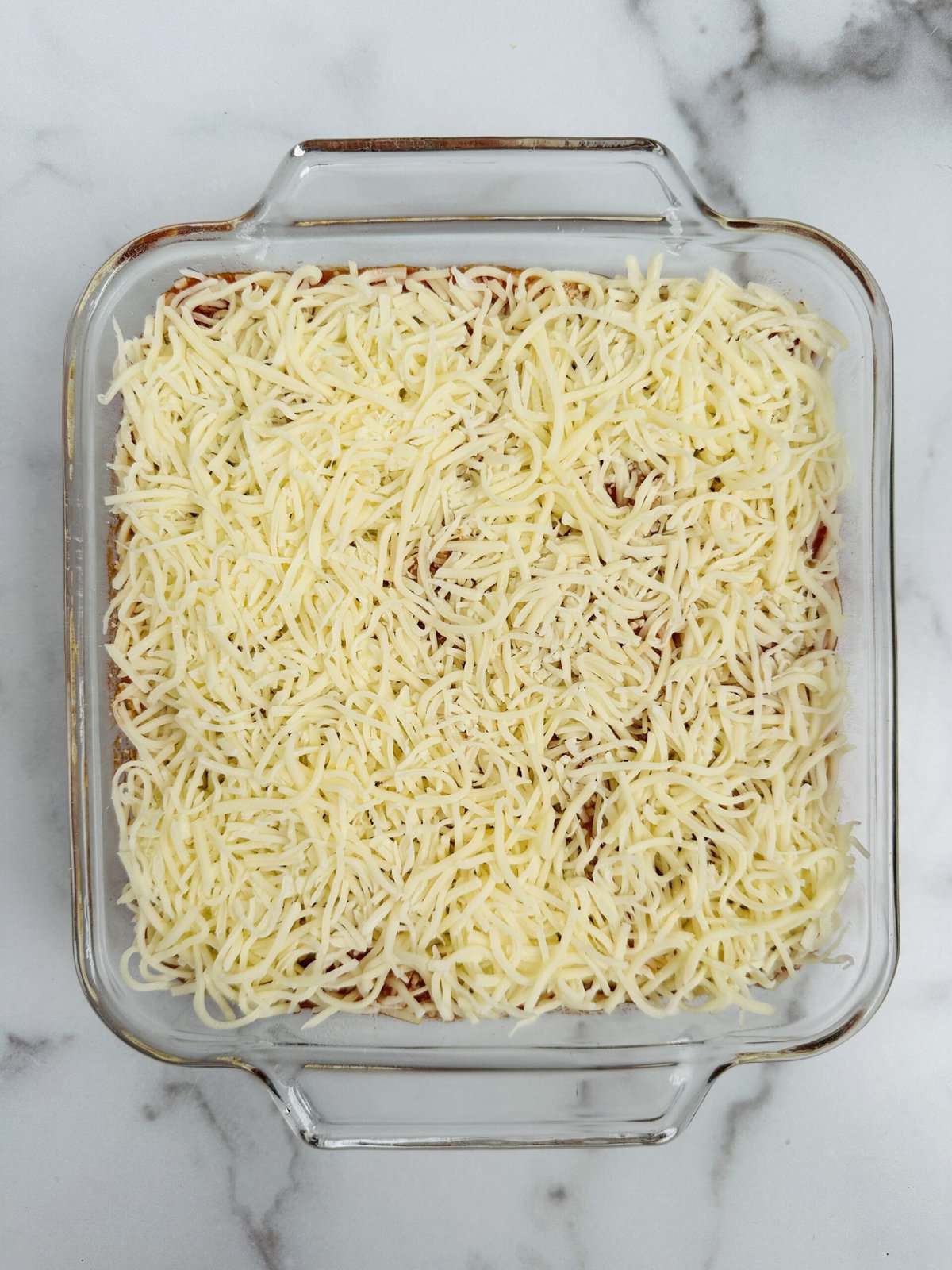 shredded Parmesan and Mozzarella cheeses evenly distributed over the cooked chicken and marinara sauce.