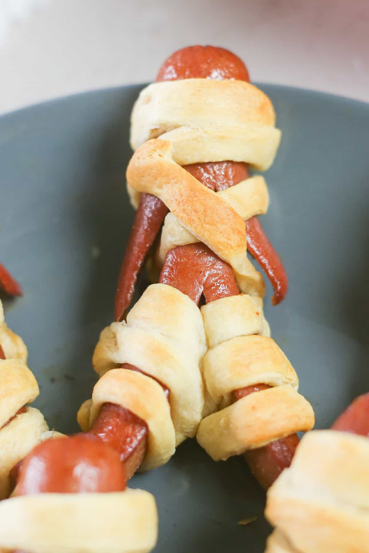 A mummy hot dog on a plate. 