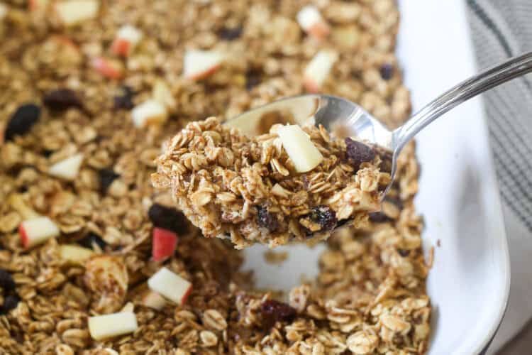 Apple cinnamon baked oatmeal in a baking dish being served with a spoon.