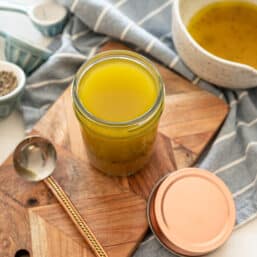 Apple Cider Vinaigrette in a small mason jar on a wooden cutting board.