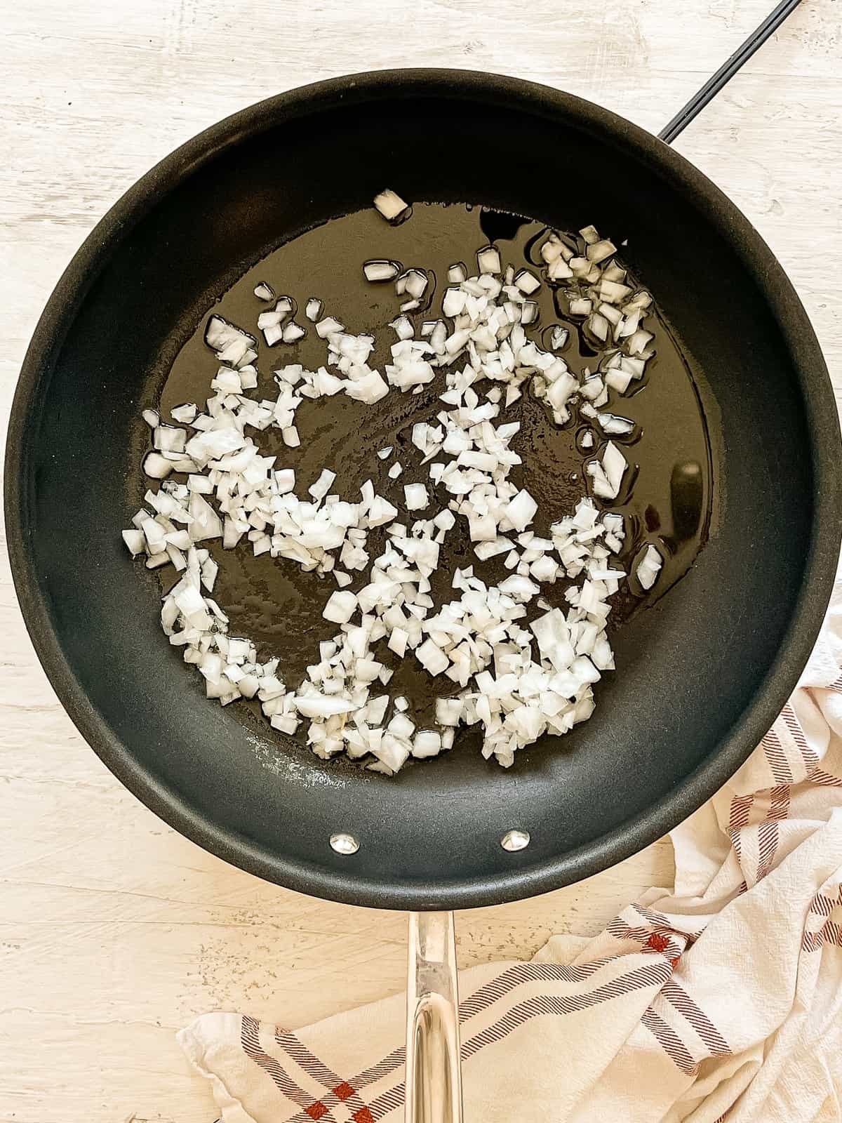 Diced onion sauteing in a black skillet.
