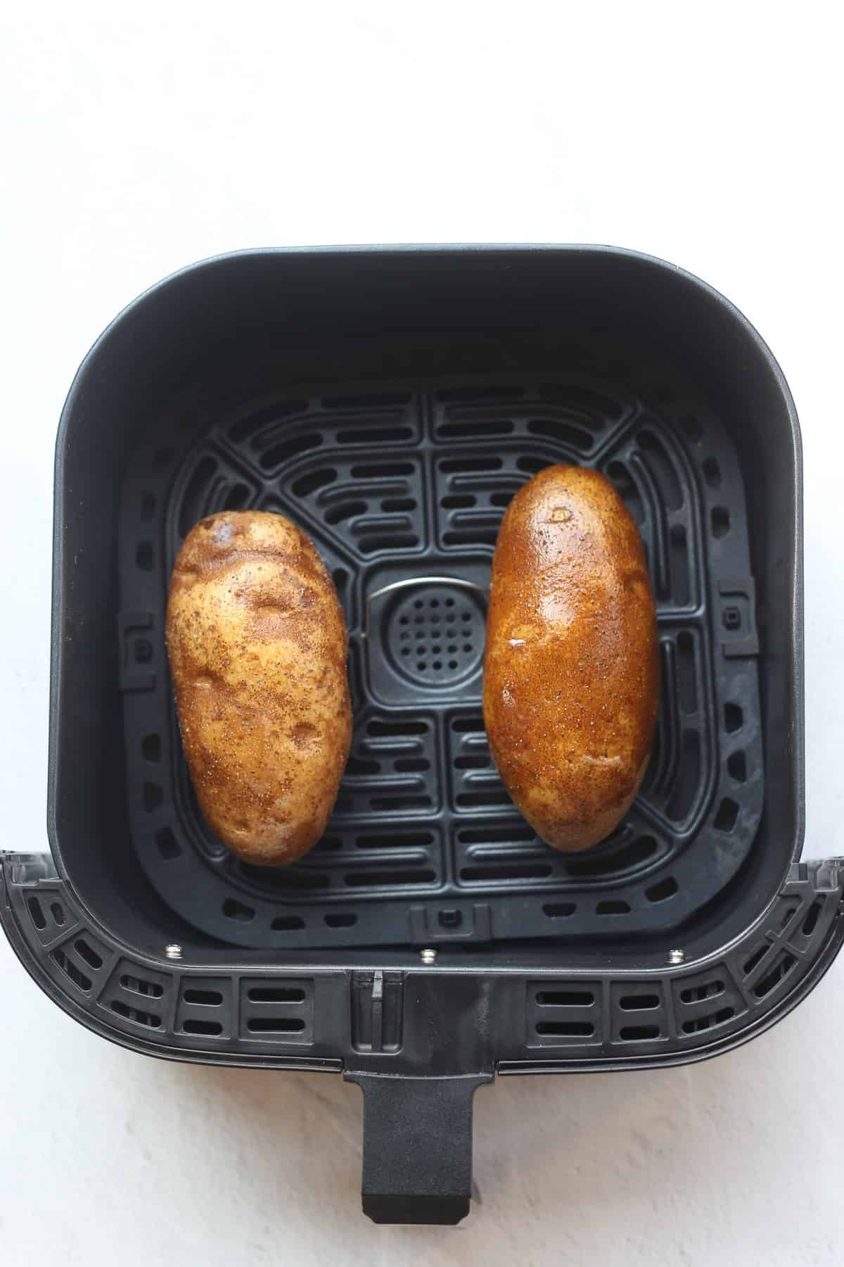 Two russet potatoes in the air fryer. 