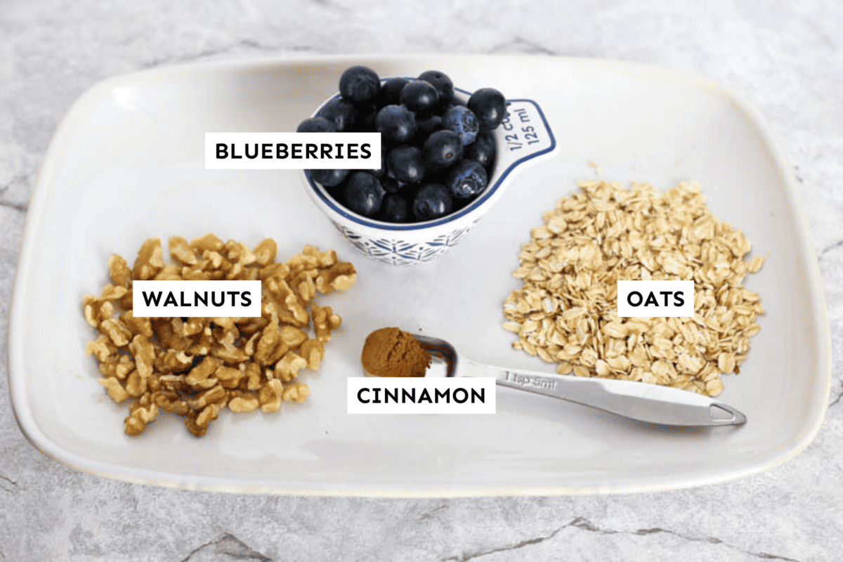 Blueberry overnight oats ingredients measured out on a white platter and labeled.