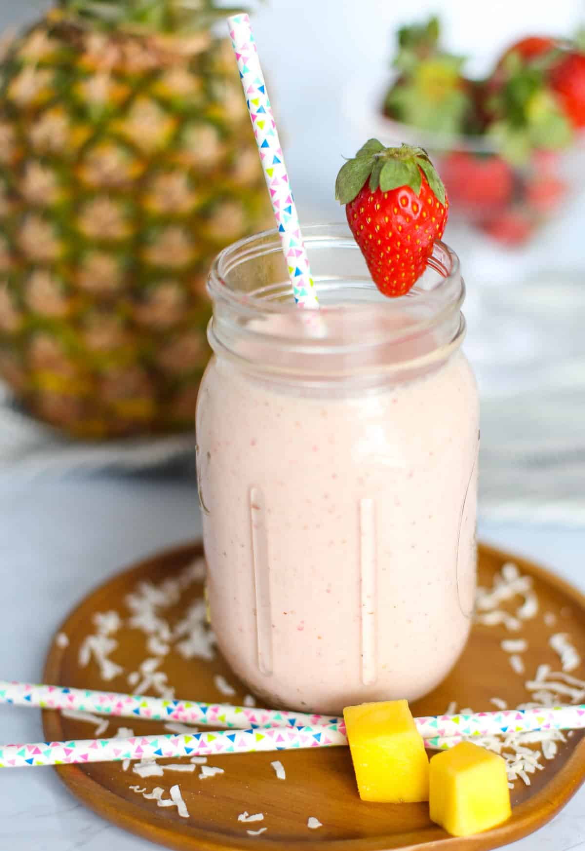 Strawberry Pina Colada smoothie in a mason jar with a decorative straw. 