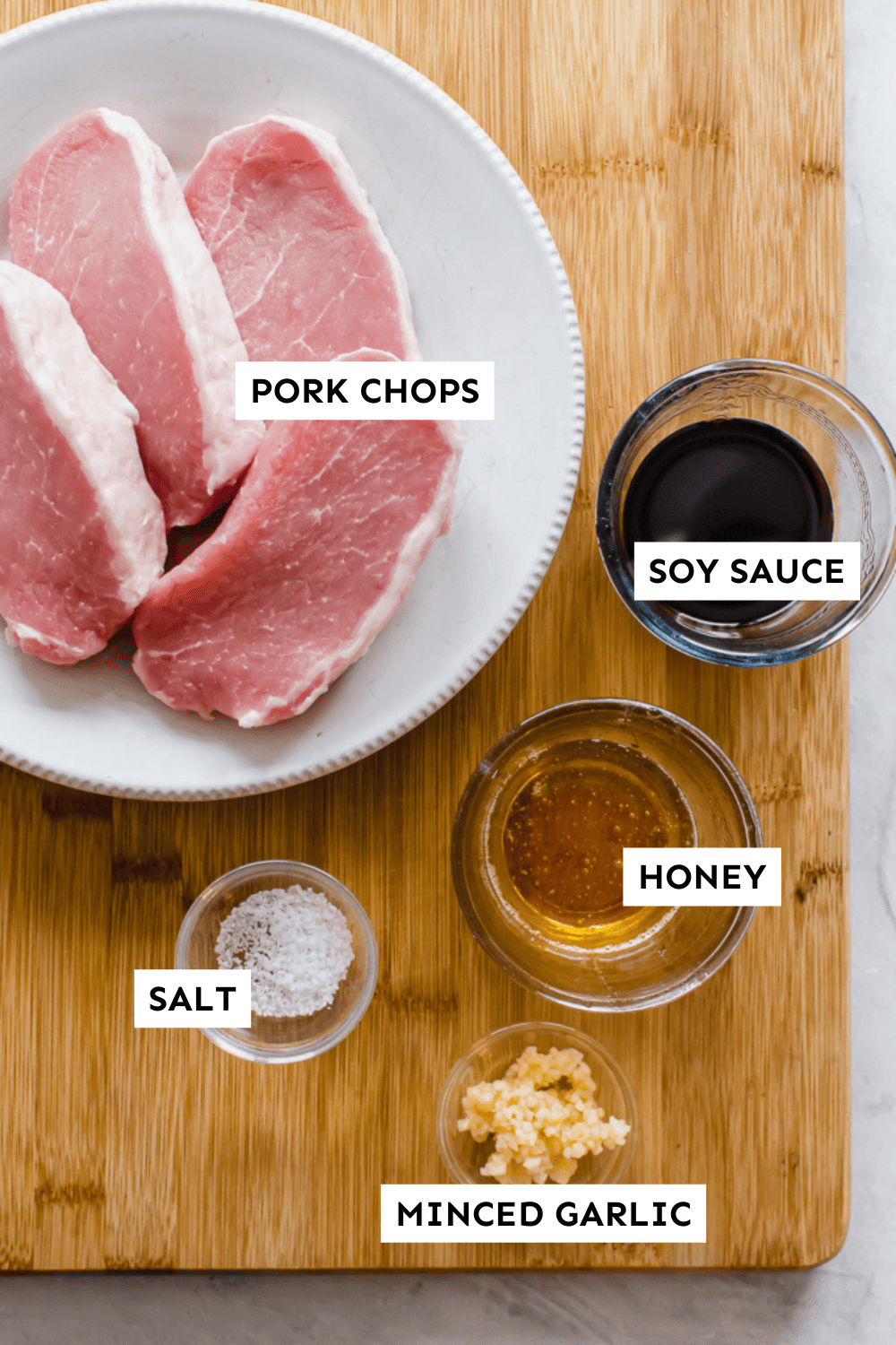 Sweet & Savory pork chop ingredients measured out in bowls sitting on a wooden cutting board and labeled.
