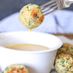Chicken meatball on a fork with honey mustard dipping sauce dripping off of it.