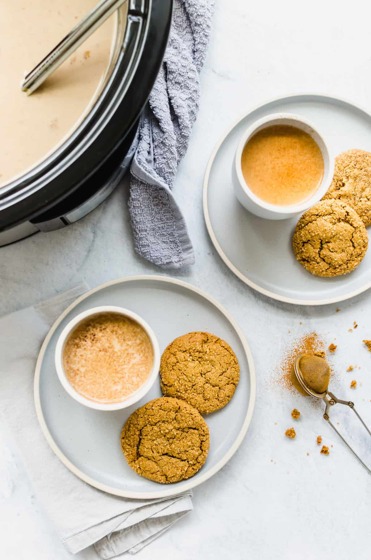 Crock pot filled with pumpkin spice latte and two mugs and cookies too