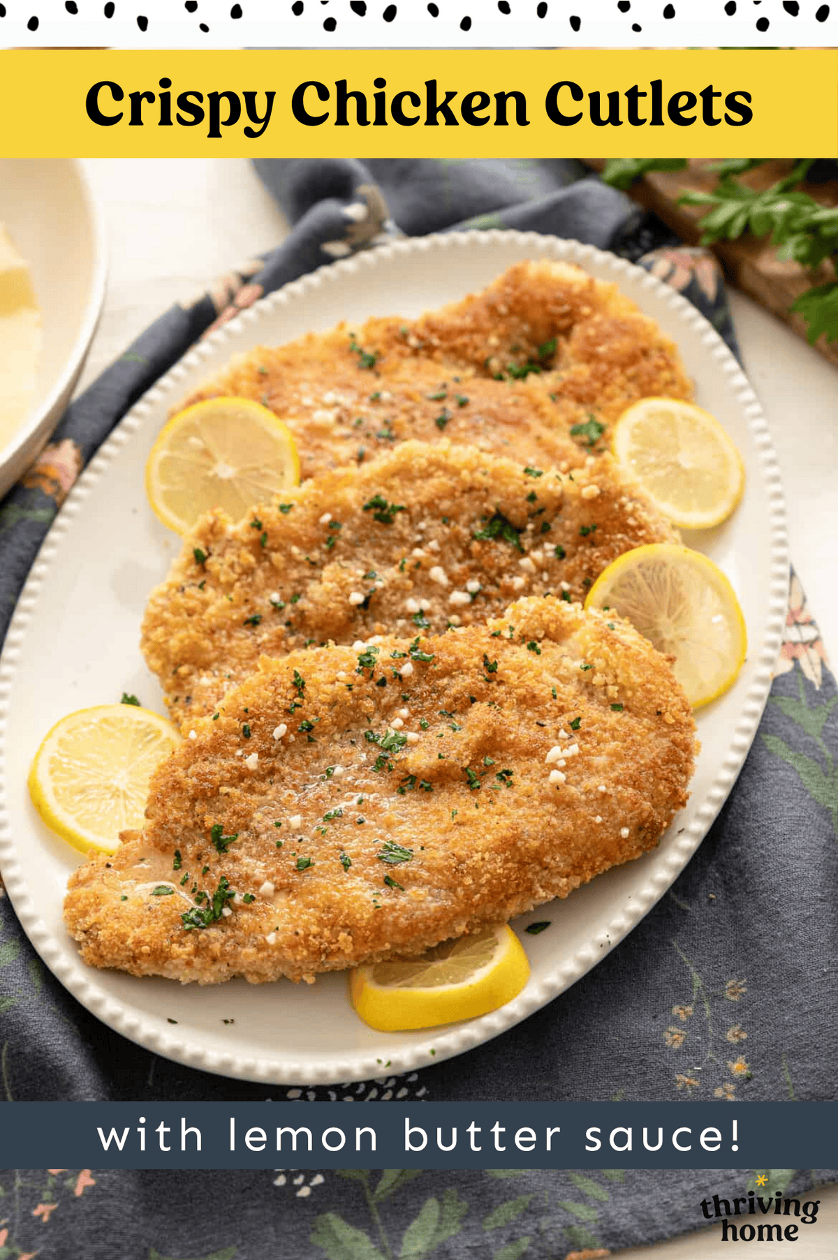 Three crispy chicken cutlets on a platter with lemon butter sauce poured over top.
