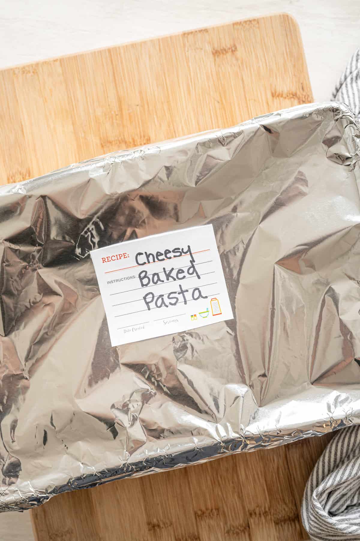 Casserole dish covered in foil and labeled Cheesy Baked Pasta.