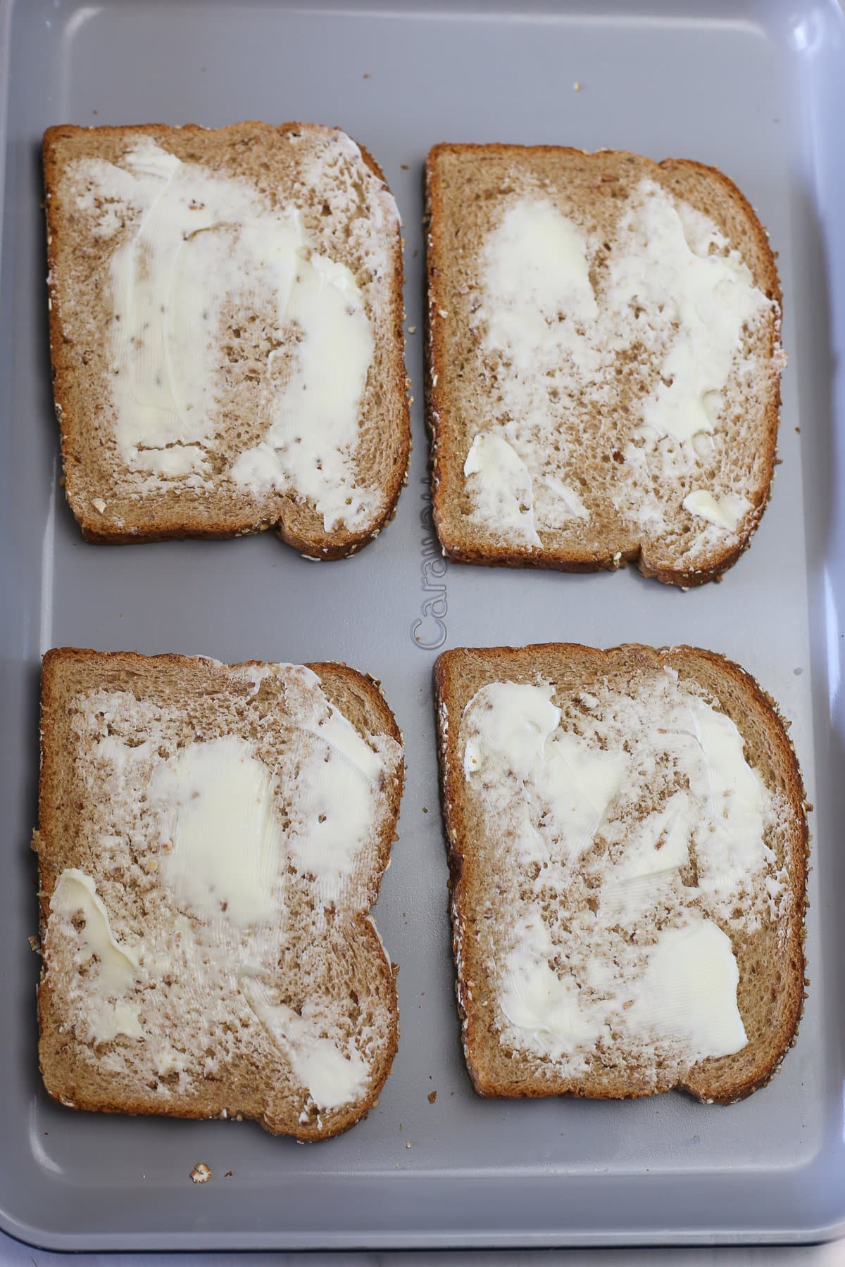 Four pieces of toast with softened butter spread out on them. 