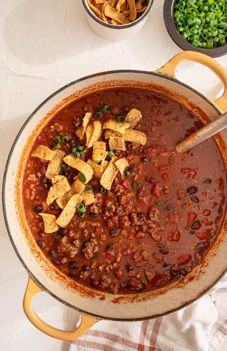 Stovetop chili in a large pot topped with fritos.