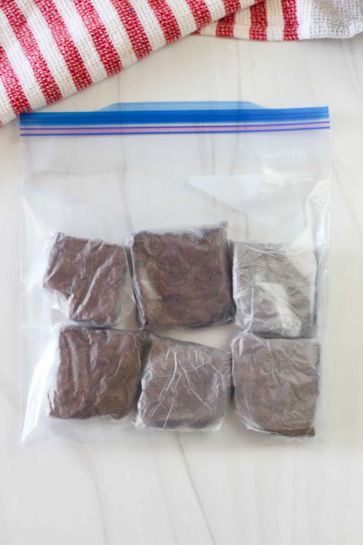 Cooked brownies wrapped in wax paper inside a freezer bag.