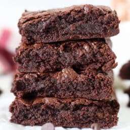 Stack of four brownies with chocolate chips sprinkled around.