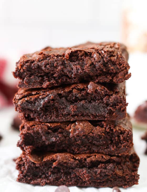 Four brownies stacked on top of each other with some chocolate chips in front.