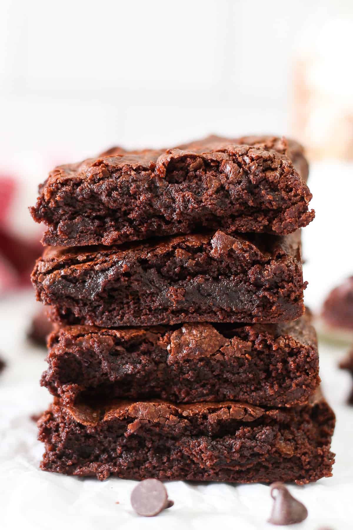 Four brownies stacked on top of each other with some chocolate chips in front.
