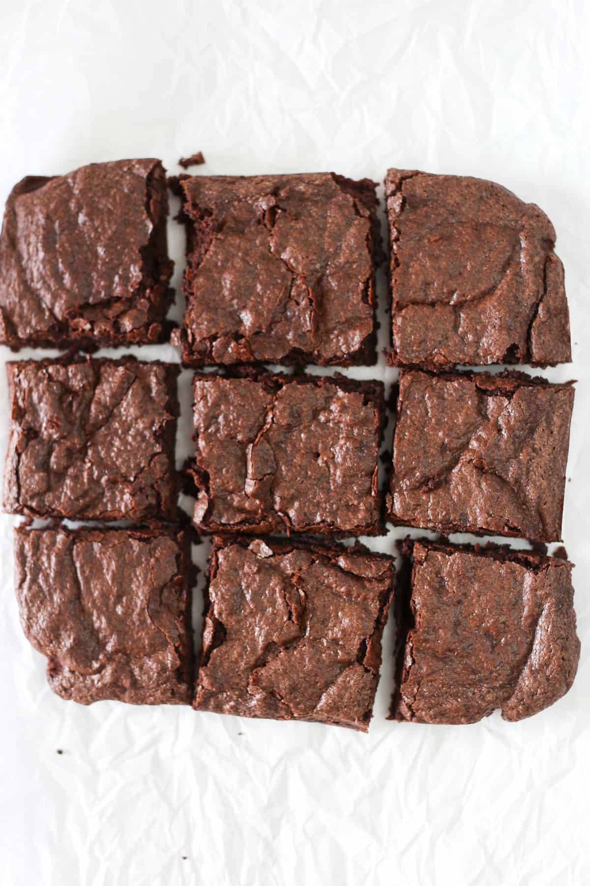 Cooked brownies on parchment paper cut into squares.