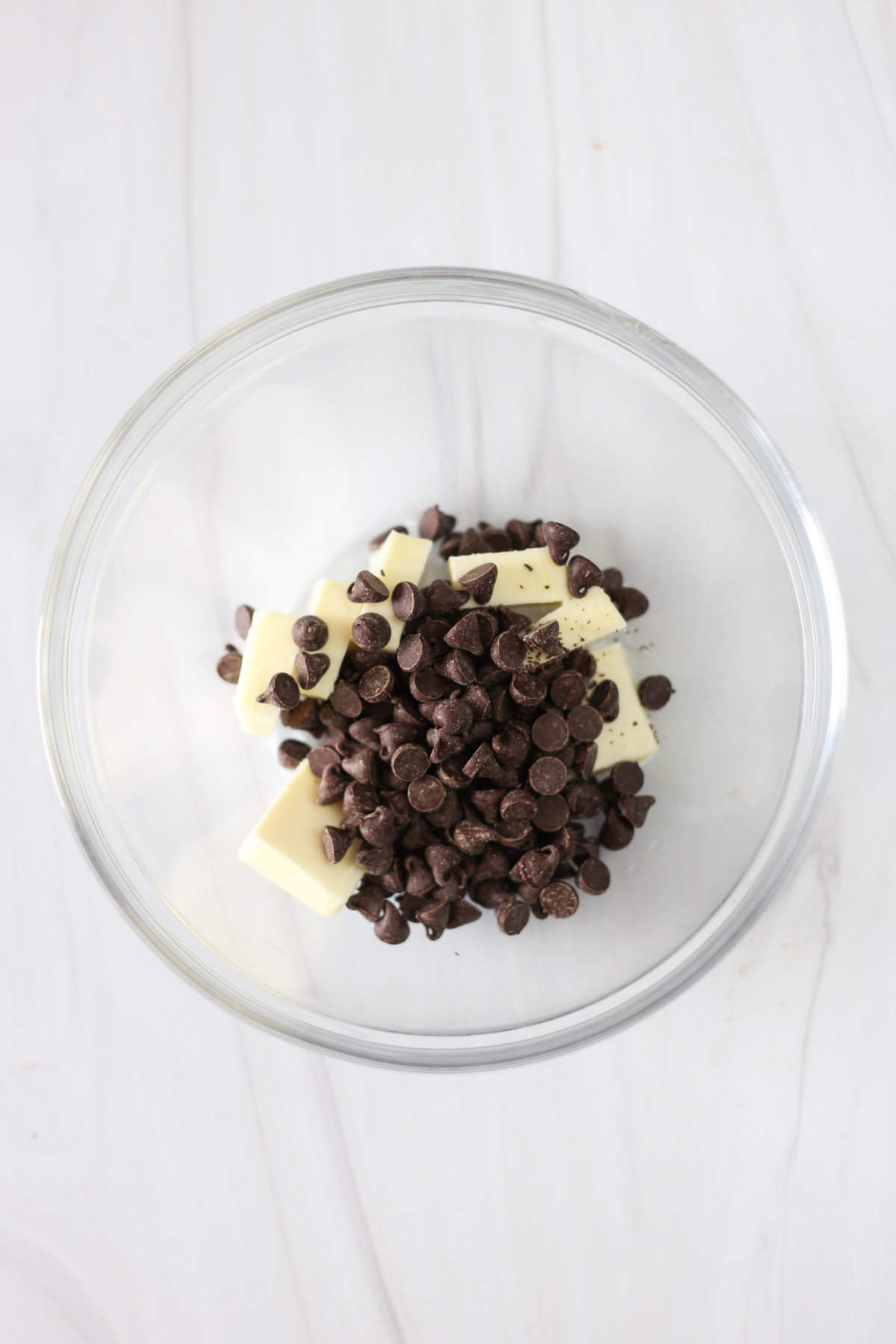 Chocolate chips and butter in a glass bowl ready to microwave.