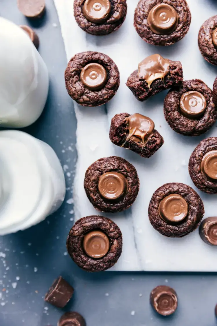 Mini brownie bites with Rolos on a piece of white marble.