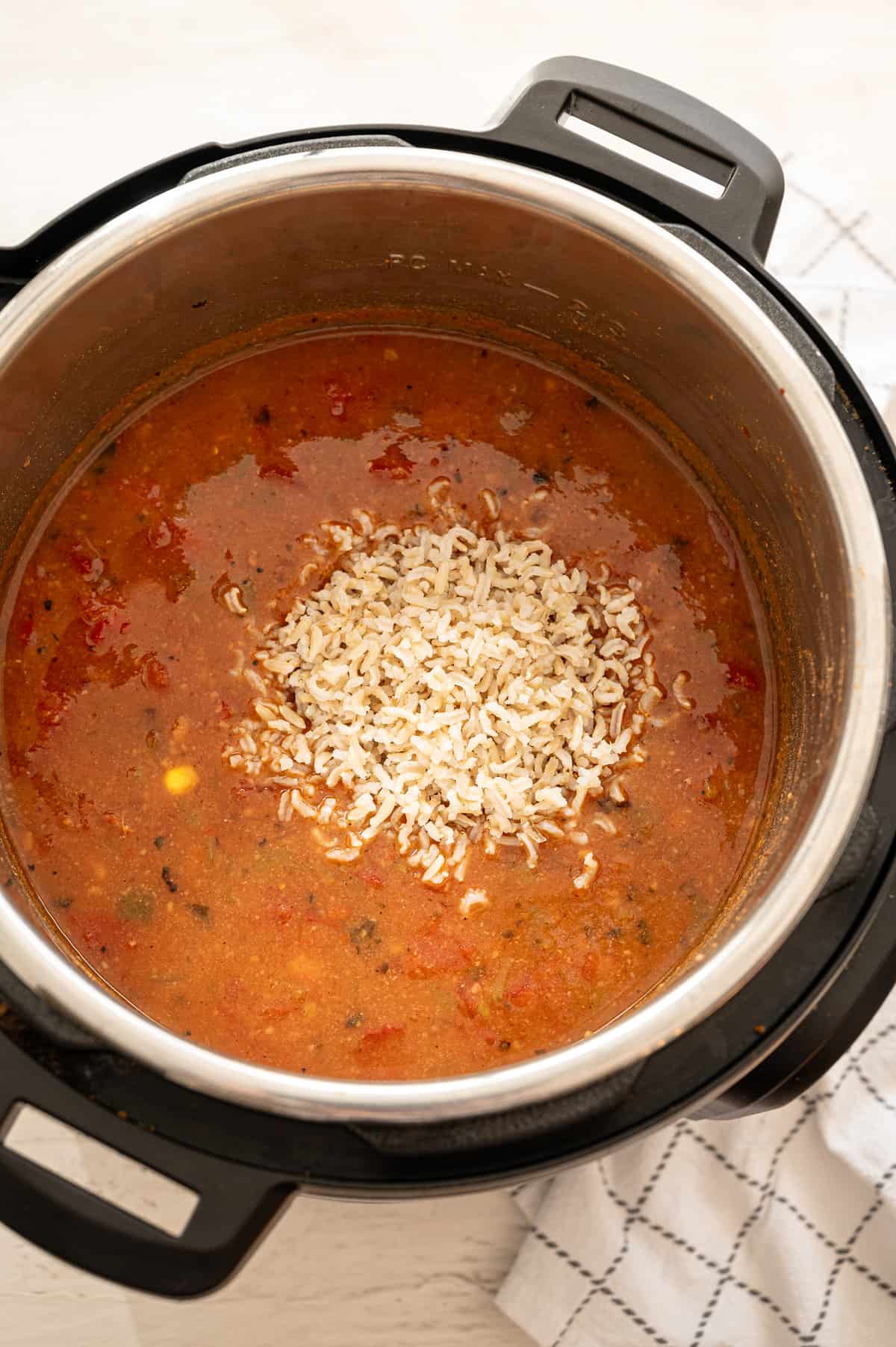 Instant Pot vegetarian tortilla soup in an Instant Pot with cooked brown rice being stirred in.