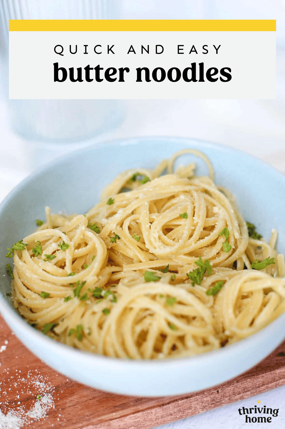 Buttered noodles in a bowl with fresh herbs on top.