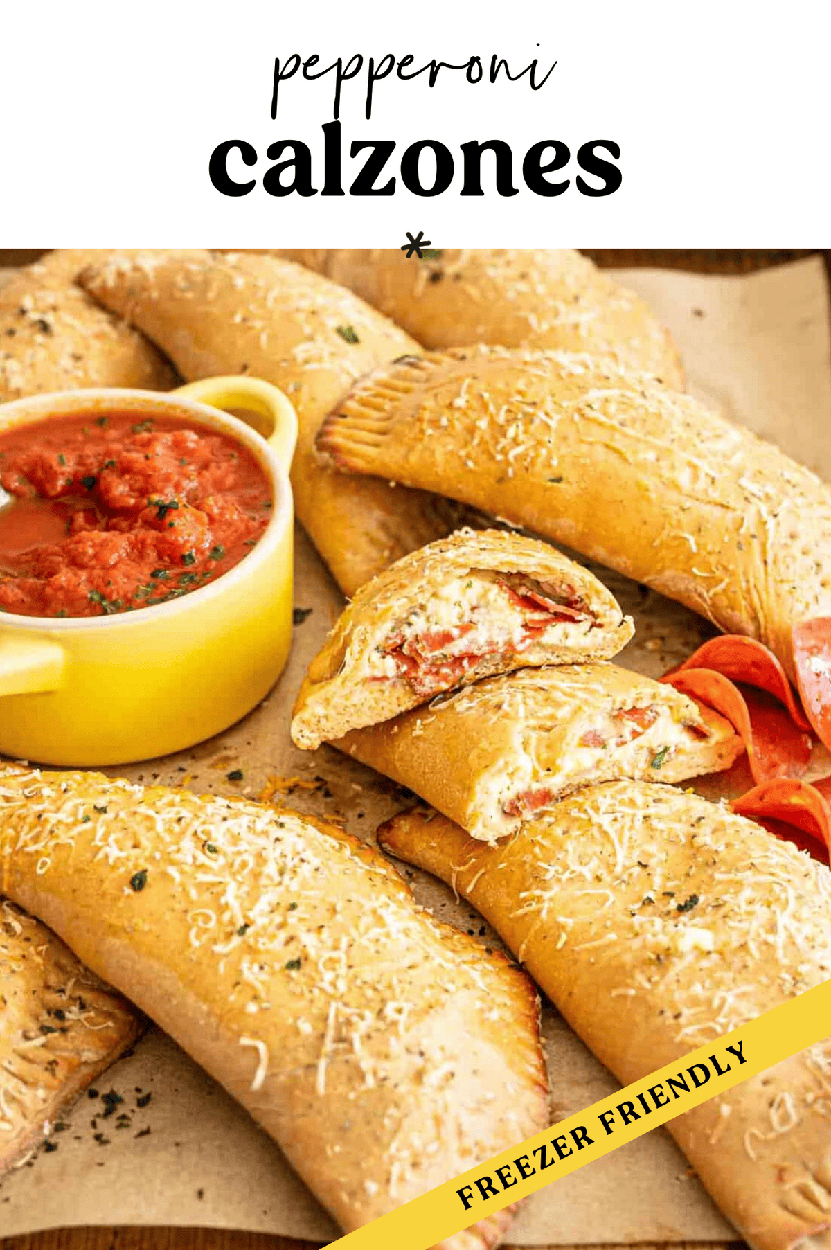 Pepperoni calzones on a parchment-lined baking sheet served with a bowl of marinara.