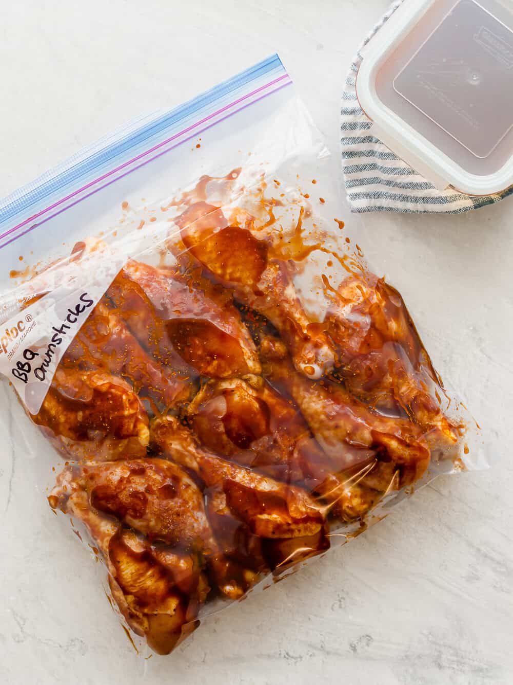 Chicken drumsticks in a freezer bag with BBQ sauce labeled BBQ drumsticks.