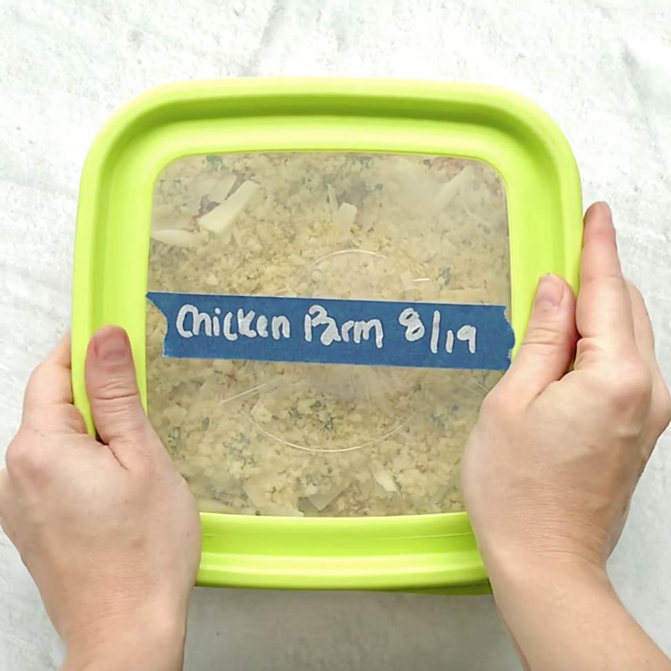 A square glass casserole dish with a lid labeled chicken Parmesan casserole.