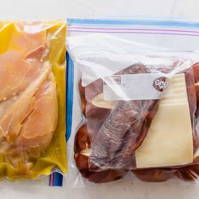 Honey Dijon chicken sandwiches packaged as a freezer meal with chicken breasts marinating in one bag, wrapped bacon and cheese slices in a bag, and pretzel buns in a third bag.