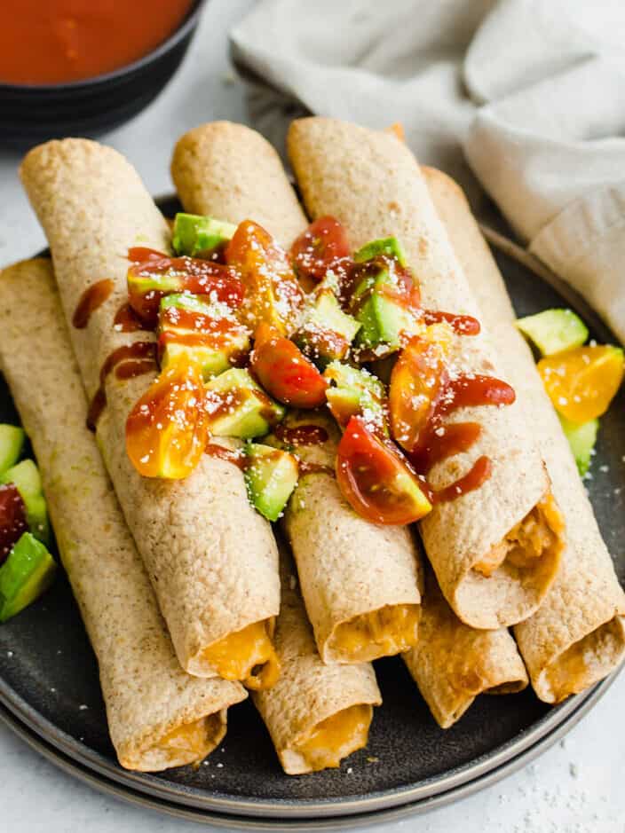 Chicken taquitos stacked up with toppings.