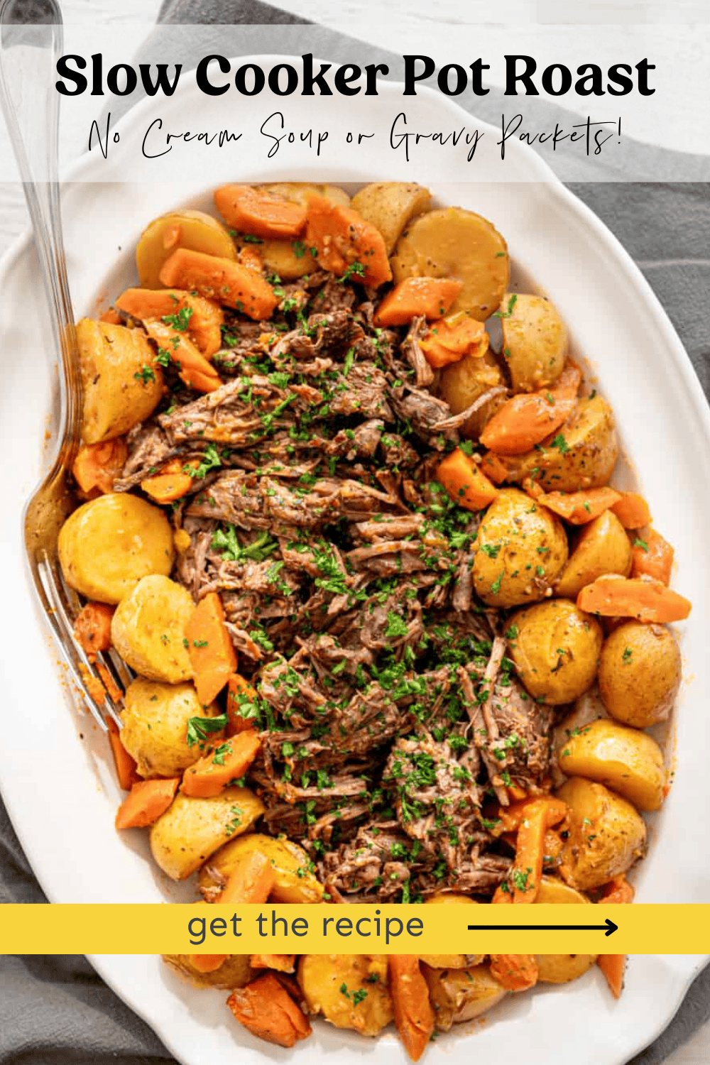 Shredded pot roast in the middle of a platter surrounded by potatoes and carrots.
