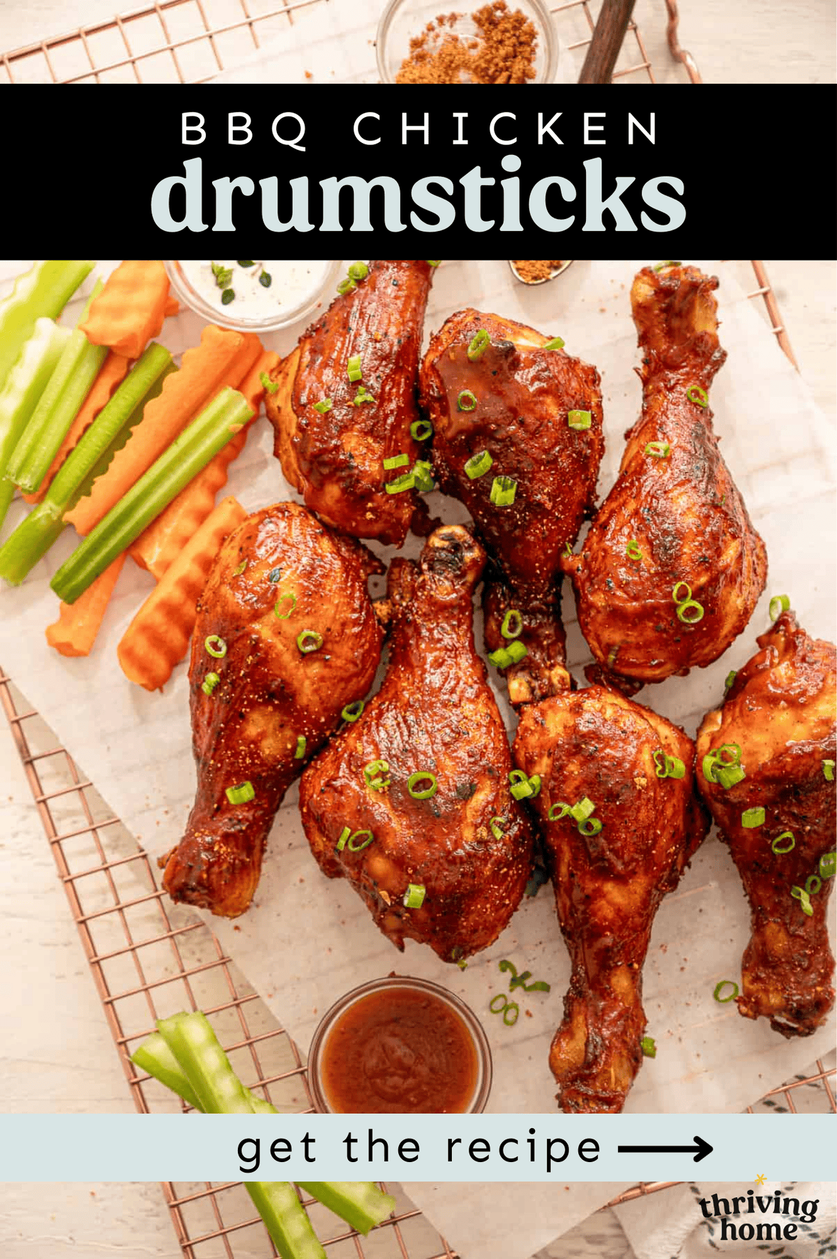 BBQ drumsticks lined up on parchment paper with celery and carrot sticks next to them.