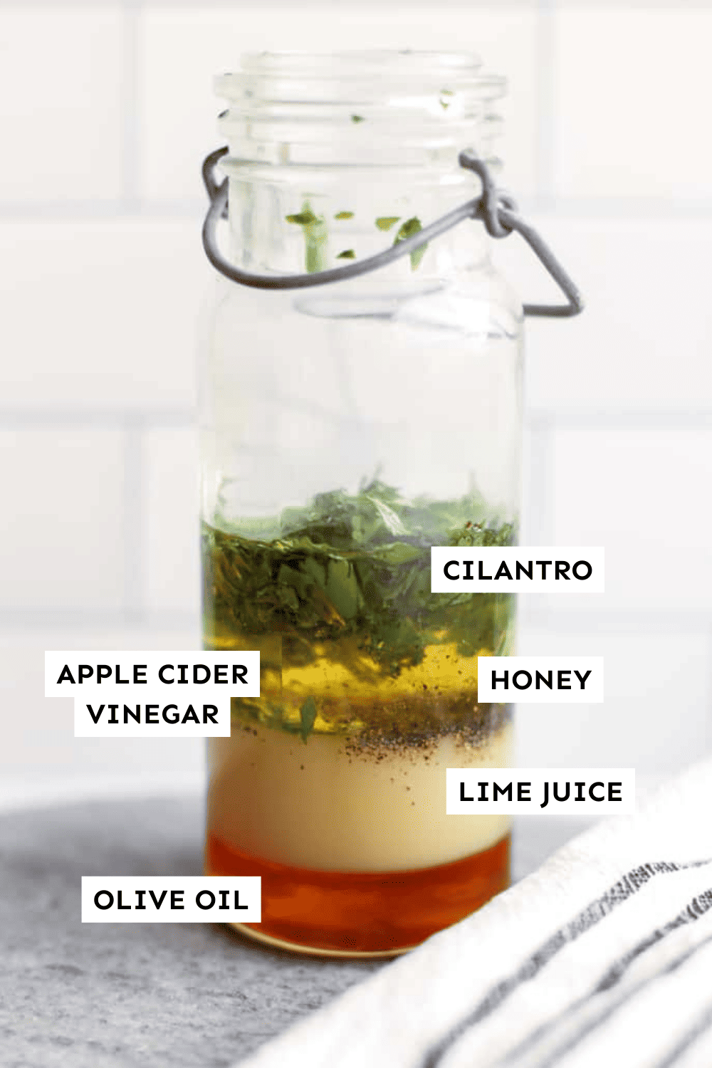 Cilantro lime vinaigrette ingredients layered in a glass bottle and labeled.