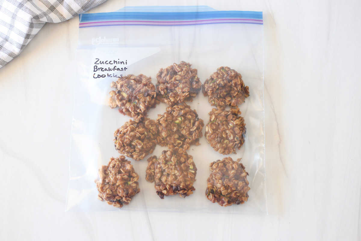 Freezer bag labeled Zucchini Breakfast Cookies on a counter with nine cookies in it.