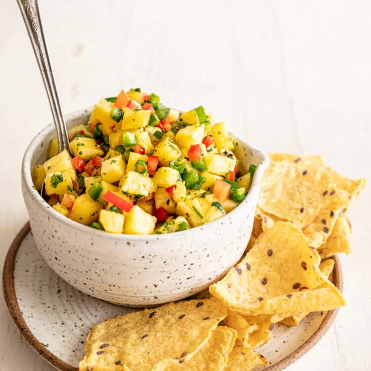 A crock of pineapple salsa with tortilla chips on the side.