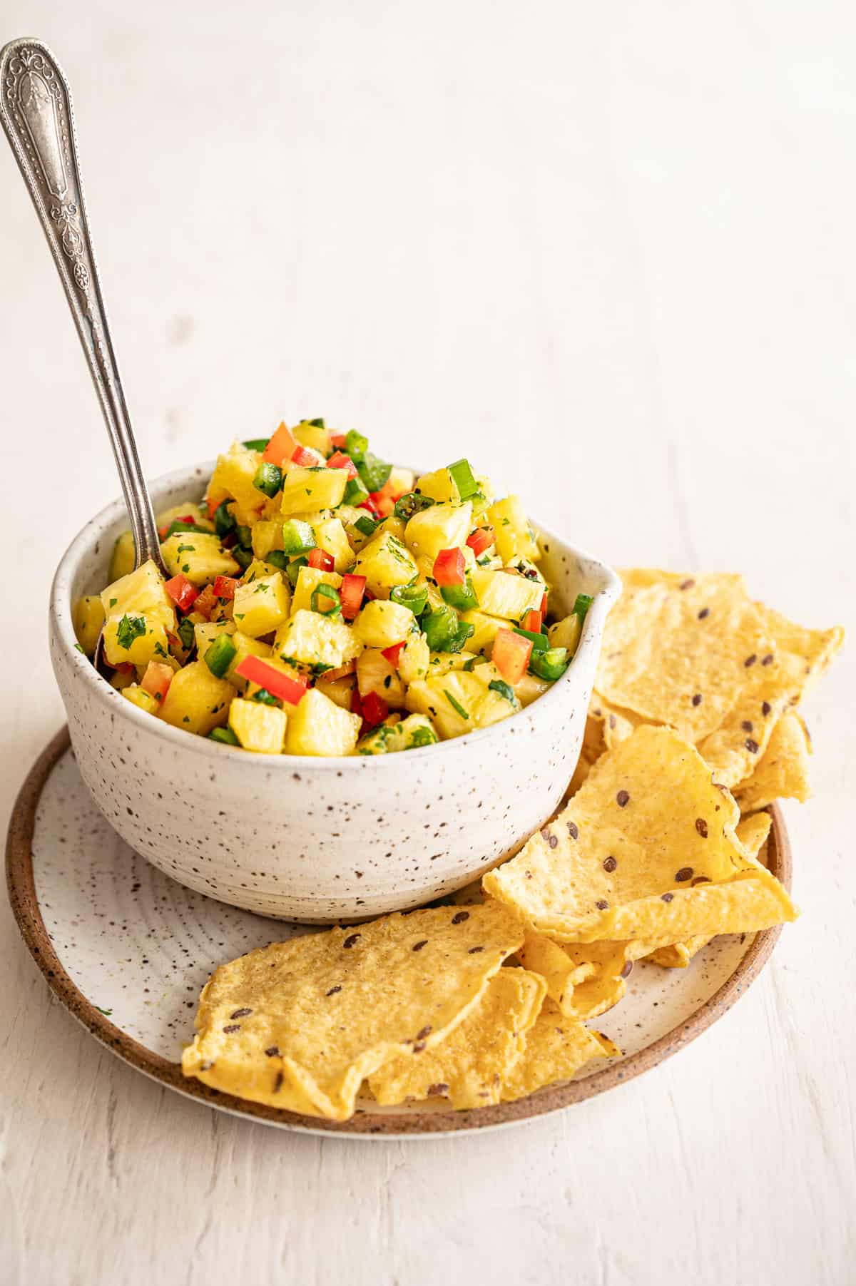 A crock of pineapple salsa with tortilla chips on the side.