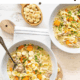 Chicken noodle soup in bowls with a small bowl of oyster crackers in between them.