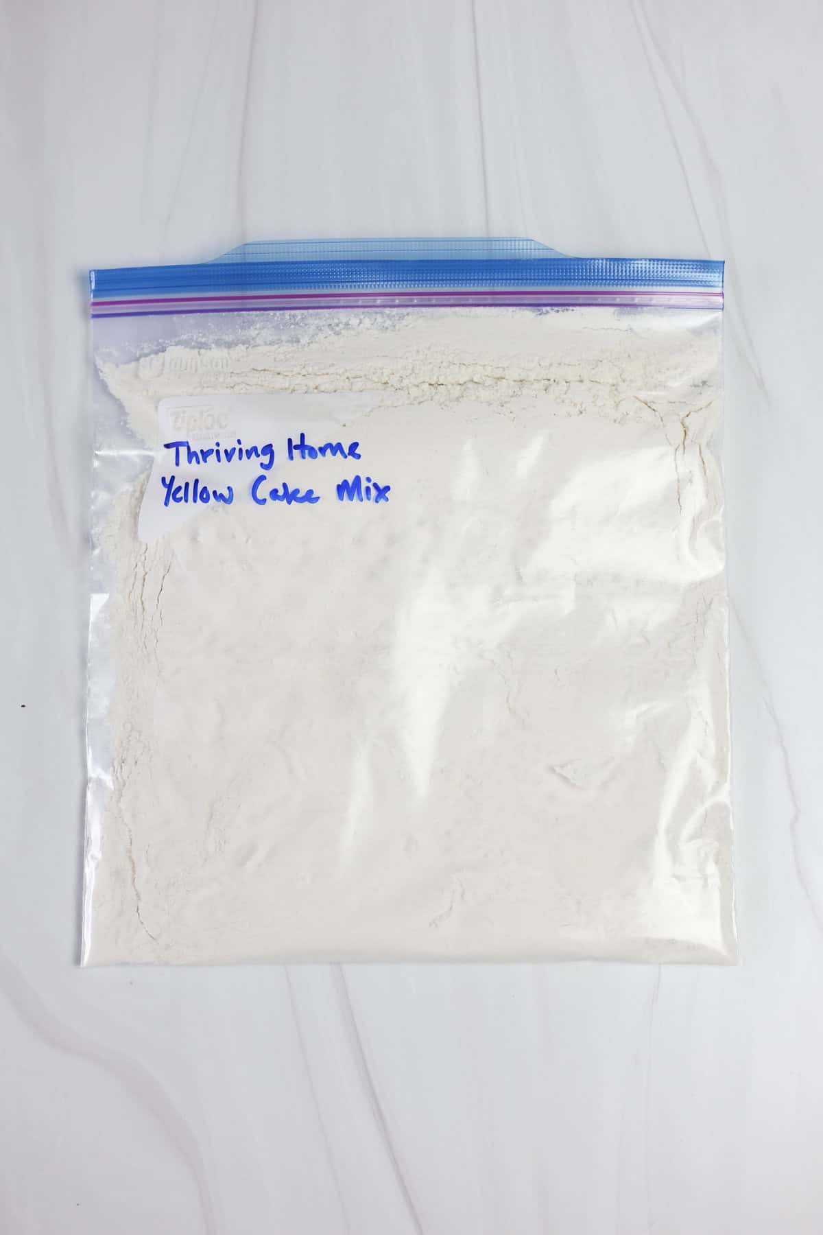 A gallon-size freezer bag labeled Thriving Home Yellow Cake Mix with dry ingredients inside.