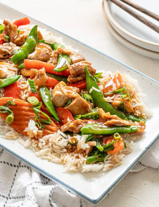A platter of honey bourbon chicken served on top of rice with stir-fried veggies.