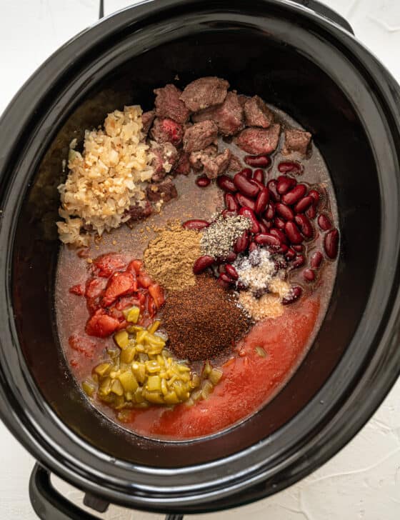 Ingredients for steak chili dumped in a slow cooker.