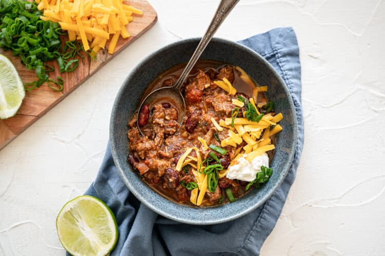 Steak chili in a bowl with toppings to the side.