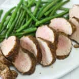 Air fryer pork tenderloin served in slices with green beans.